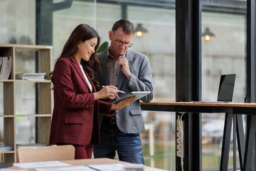 Two business working together using digital tablet pc and talking about a business project. Small creative diversity team of females executives meeting work in office.
