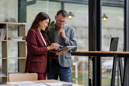 Two business working together using digital tablet pc and talking about a business project. Small creative diversity team of females executives meeting work in office.
