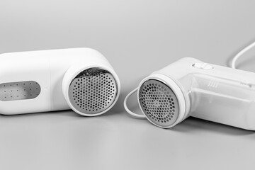Monochrome shot of two electric fabric shavers on a grey background. These lint removers are...