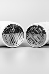 Monochrome close-up of two electric fabric shavers, focusing on the metallic shaving screens. Essential tools for refreshing your garments and removing pilling.


