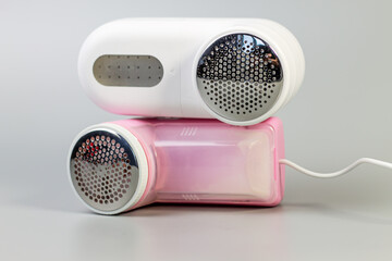A pair of electric fabric shavers in white and pink, stacked on a grey background. Keep your favorite textiles looking fresh and pill-free!

