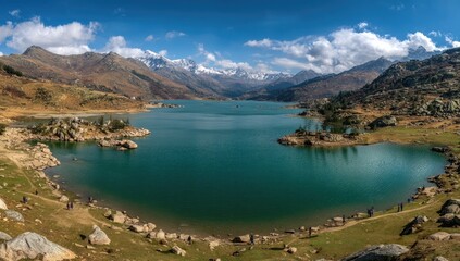 Fototapeta premium Expansive vista of a serene blue lake nestled amidst majestic mountains under a clear sky