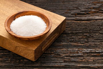 Saccharum officinarum - Fine crystals of refined white sugar on a wooden bowl