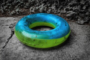 A faded, circular pool float rests on a gray concrete path
