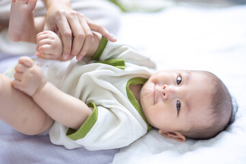Asian newborn baby boy lying on the floor. Happy baby boy in kindergarten or daycare. Child playing in preschool. 