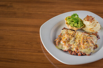 Grilled Steak Topped with Melted Cheese, served with Mashed Potatoes and Guacamole
