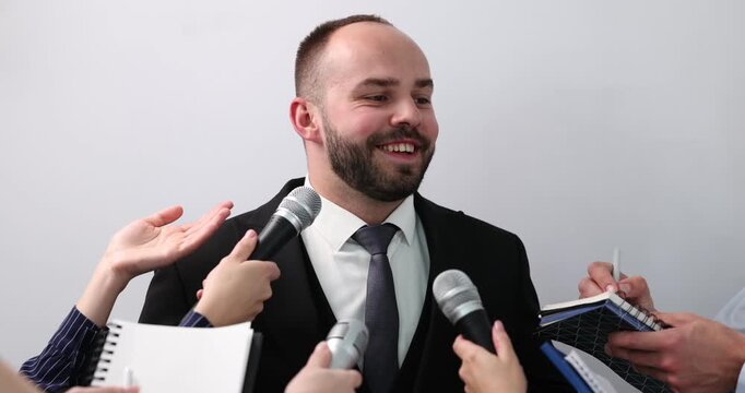 Businessman giving interview to journalists on light background