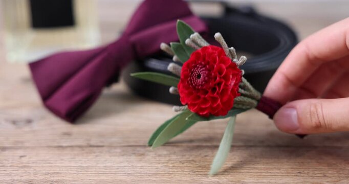 Woman taking stylish boutonniere at wooden table, closeup