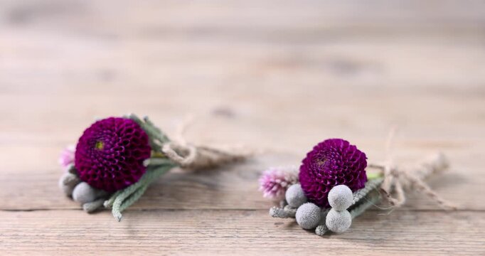 Woman taking stylish boutonniere at wooden table, closeup