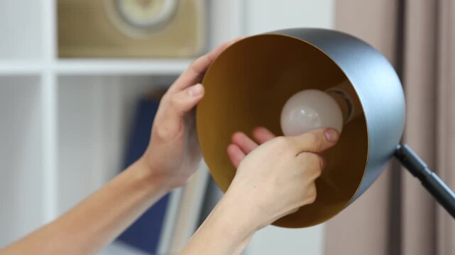 Woman changing light bulb in lamp at home, closeup