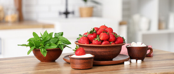 Bowls with tasty strawberries, sugar and mint on table in kitchen