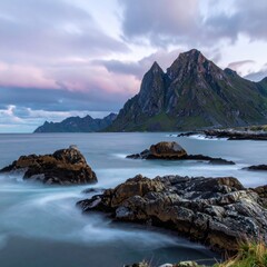 A picturesque coastal scene featuring rugged mountains, calm sea, and dramatic sky.