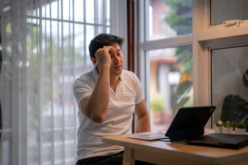 Stressed asian freelancer having headache while working from home