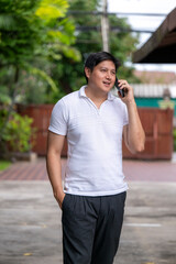 Asian man walking and talking on smartphone outdoors