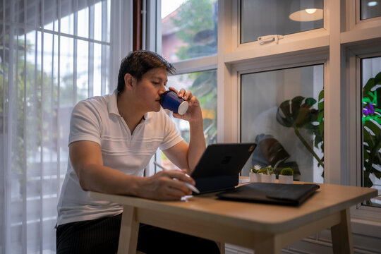 Asian freelancer drinking coffee and working from home office