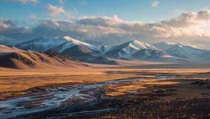 Vast, snow-capped mountain range, golden plains, and a winding river under a dramatic sky