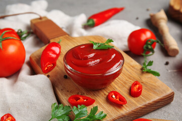 Composition with bowl of tasty ketchup and ingredients on grey grunge background, closeup
