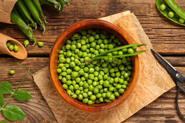 Bowl with fresh green peas on wooden background, closeup