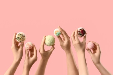 Female hands with different bath bombs on pink background