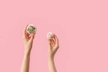 Female hands with bath bombs on pink background