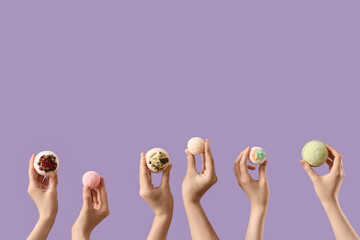 Female hands with different bath bombs on lilac background