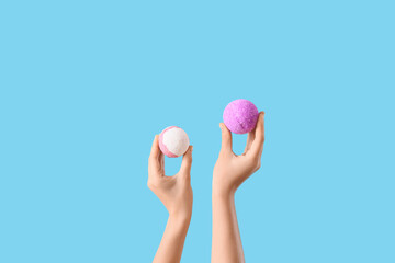 Female hands holding bath bombs on blue background