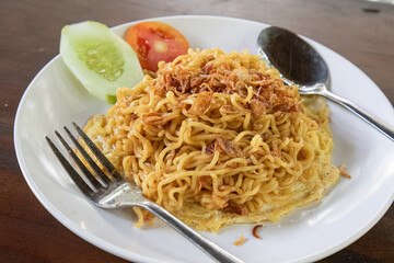 Fried noodles with crispy onions and fresh veggies. Asian fried noodles with fresh garnish on plate. Quick fried noodles meal with vegetable garnish. Savory fried noodles with side veggies and garnish