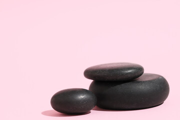 Black pebbles on pink background. Zen concept