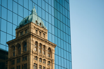 AI generated photograph showcasing the stunning reflection of a historic building on the sleek glass panels of a modern skyscraper. A fusion of architectural styles and light.
