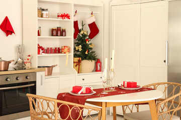 Interior of light kitchen with Christmas tree, cupboard and dining table