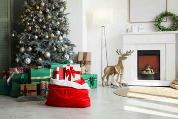 Obraz premium Santa bag with presents and Christmas tree in living room interior