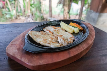 Grilled chicken steak with colorful veggies served hot. Juicy chicken steak with fresh veggies on sizzling plate. Tender grilled chicken with steamed vegetables on plate. Sizzling hot chicken steak