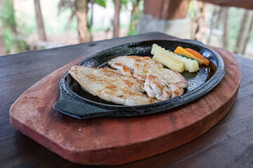 Chicken steak sizzling on hot skillet with veggies. Delicious grilled chicken served with fresh vegetables. Tender chicken and veggies sizzling hot. Grilled chicken steak and fresh sides served hot