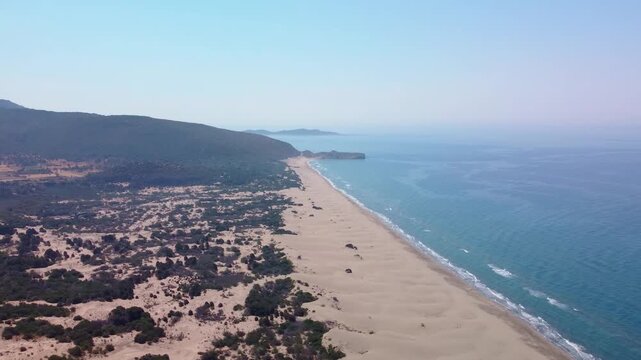 aerial drone shot showcasing the expansive Patara Beach, its golden sand dunes, and the clear blue Mediterranean Sea in Antalya, Turkey. This footage captures the natural beauty of one of Turkey's lon