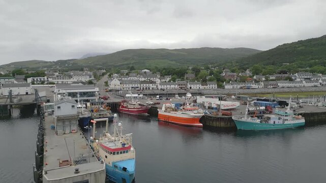 Fishing boats docked in Ullapool harbour on Loch Broom in Scottish Highlands with town and hills