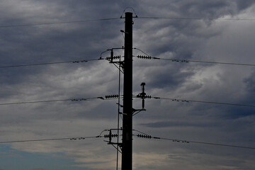 Silhouette of high voltage transmission lines on stormy day with cut out switches all protected by overhead ground wire, OHGW.