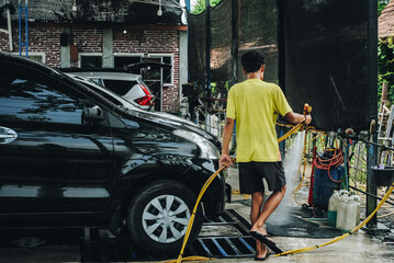 A car wash worker washing a car at a car wash station.