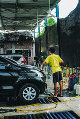 A car wash worker washing a car at a car wash station.