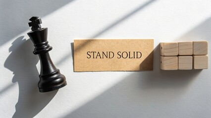 Black chess piece next to wooden blocks and card with motivational text showcasing focus on strength and determination in life