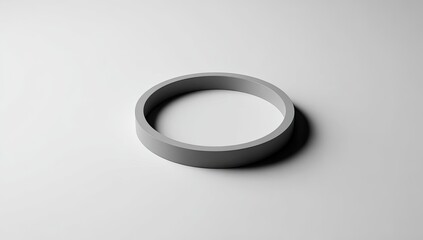 A minimalist, gray cylindrical ring casts a shadow on a plain white surface