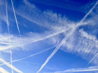 Clear blue sky with many white contrails crossing in different directions