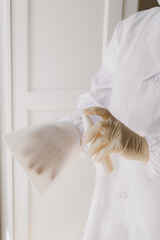 A nurse soaks a disposable textile glove with medicine.
