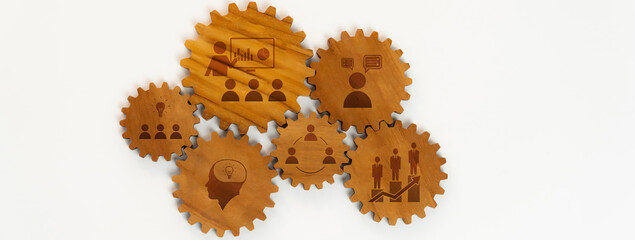 This image features wooden gears symbolizing various business concepts such as teamwork and collaboration, with icons that illustrate communication, growth, and planning effectively. Amity