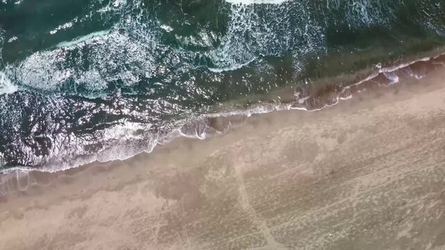 aerial drone shot showcasing the pristine Patara Sand Dunes meeting the turquoise Mediterranean Sea in Turkey. Gentle waves roll onto the expansive sandy beach, highlighting the natural beauty and tra