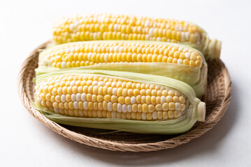 Fresh sweetcorn (bicolor) in basket on white background
