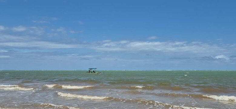 walking on the beach jangada boat passing on the horizont patacho beach alagoas Brazil