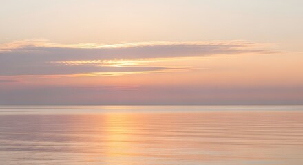 Obraz premium Serene coastal sunrise over calm ocean waters with soft pastel sky reflections