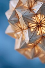 Close-up of a light fixture.  Complex, light-wood origami-like structure.  Geometric patterns and shapes.  Soft, warm light emanating.  Abstract design against a muted blue background