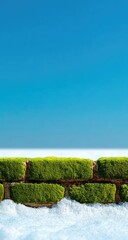 A vibrant green moss-covered brick wall, set against a clear cerulean sky.  A line of snow sits at the base