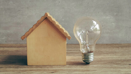 Light Bulb and Wooden House Model Representing Energy Efficiency, Smart Home Idea, and Property...